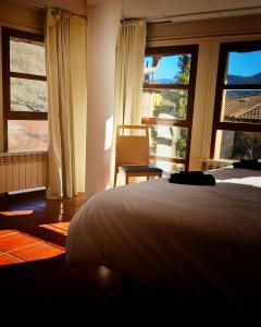 um quarto com uma cama e janelas grandes em La Villa em Canales de la Sierra