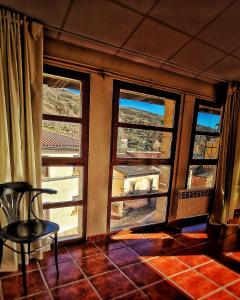 Habitación con 3 ventanas, silla y mesa. en La Villa en Canales de la Sierra