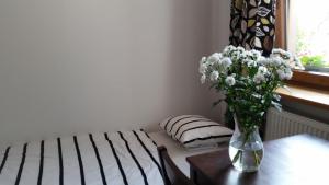 a vase of flowers on a table next to a bed at Noclegi na Wróbla in Olsztyn