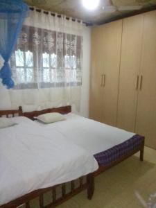 a bedroom with a bed and a window with a curtain at VA Villa Hikkaduwa in Hikkaduwa