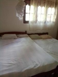 a bedroom with two white beds and a window at VA Villa Hikkaduwa in Hikkaduwa
