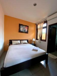 een slaapkamer met een groot wit bed met oranje muren bij The Friz Arimanu in Kuta