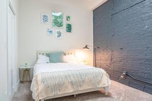 a bedroom with a white bed and a brick wall at McCormick Place 420 friendly 3BR/2BA with Optional parking for up to 8 guests in Chicago