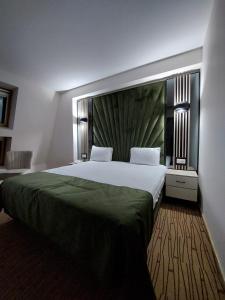 a bedroom with a large bed with a green headboard at Hotel Wolf 2 in Bran