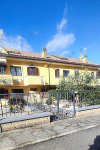 uma casa amarela com uma cerca em frente em Civico 4 em Campagnano di Roma