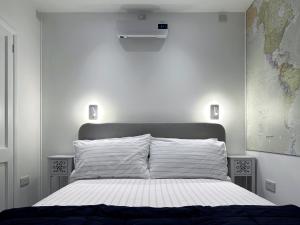 1 dormitorio con cama blanca y mapa en la pared en Kensington Studio hosted by AirOperate near Notting Hill - 1 Double Bed , 1 Sofa Bed, Ground Floor Apartment via Private Entrance en Londres