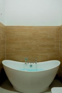 La salle de bains est pourvue d'une baignoire blanche et d'un mur en bois. dans l'établissement Radawana Wasala Nature Resort, à Radawana