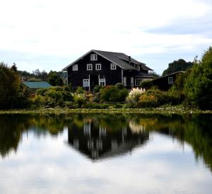 a house reflected in the water of a lake at Hotel Boutique Casa Werner in Puerto Varas