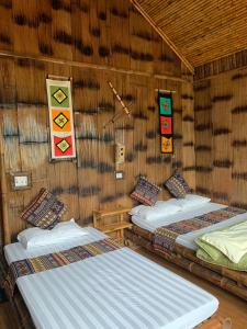 um quarto com duas camas numa parede de palha em Mai Chau La Vida Homestay em Mai Châu