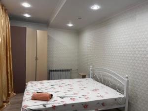 a bedroom with a white bed with flowers on it at Первая береговая линия, набережка in Aktau
