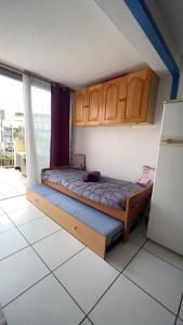 Schlafzimmer mit einem Bett mit Holzschränken und einem Kühlschrank in der Unterkunft Appartement climatisé avec grande terrasse SUD in Gruissan