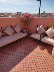 zwei Bänke auf einem Balkon mit Blumen in der Unterkunft Dar Dadès in Marrakesch