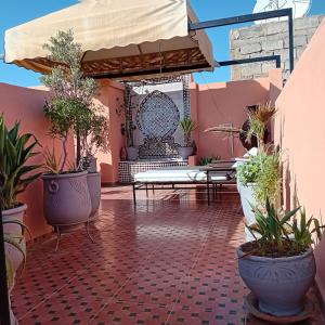 eine Terrasse mit Topfpflanzen an einer rosa Wand in der Unterkunft Dar Dadès in Marrakesch