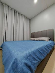 um quarto com uma cama com um cobertor azul em Coz26 Bercham House Spacious Family Suite 14pax 3Parking em Ipoh