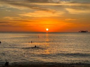 een zonsondergang op het strand met mensen in het water bij Tropical Bay Grand World Phu Quoc in Phu Quoc