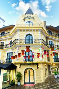 a yellow building with red chairs on the balcony at Babeeni Family Hotel Sapa in Sa Pa