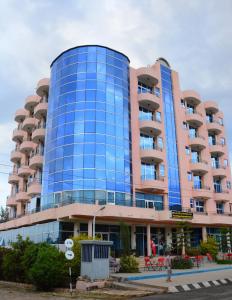 ein hohes Gebäude mit blauen Fenstern auf einer Straße in der Unterkunft Yaredzema International Hotel in Aksum