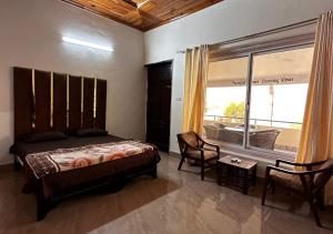 a bedroom with a bed and a large window at PINETOP RESORT in Khānpur