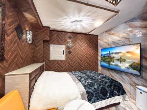 1 dormitorio con 1 cama y TV en la pared en Hotel BaliBali 鶯谷, en Tokio