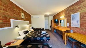 Habitación de hotel con cama y pared de ladrillo en Early Australian Motor Inn, en Mildura