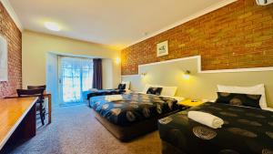 a hotel room with two beds and a brick wall at Early Australian Motor Inn in Mildura