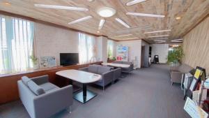 a waiting room with chairs and a table and a tv at Hotel Select Inn Tsuyama in Tuyama