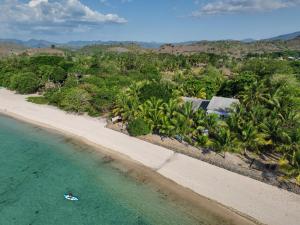 an aerial view of a beach with a person in the water at Myamo Beach Lodge in Jereweh