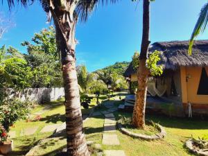 a house with palm trees in front of it at JEJU Cottages in Kuta Lombok