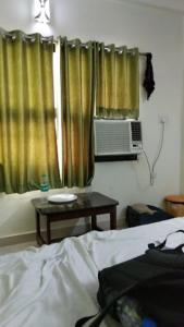 a bedroom with a bed and a table and curtains at Hotel Golden Leaf , Sagar in Sāgar