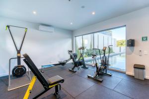 een fitnessruimte met loopbanden en hometrainers in een kamer bij Oceanus oasis at Bokarina Beach -stunning modern coastal apartment in Kawana Waters