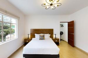ein Schlafzimmer mit einem weißen Bett und einem Kronleuchter in der Unterkunft Cadetes 47 #302 in Mexiko-Stadt
