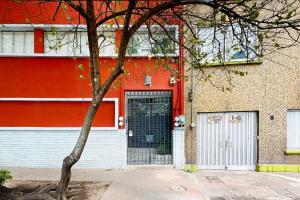 ein rotes Gebäude mit einer Tür und einem Baum in der Unterkunft Cadetes 47 #302 in Mexiko-Stadt