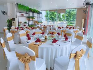 un salón de banquetes con mesas blancas y sillas con flores. en Galaxy Grand Hotel, en Sơn La