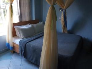 um quarto com uma cama com cortinas e uma janela em TAPHE GUEST RESORT em Naivasha