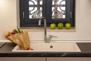 a kitchen sink with apples on a window ledge at Simo's Apartments in Egina