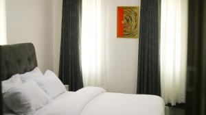 a bedroom with a bed with white pillows and curtains at Victoria Homes - Lekki Apartment Lekki Phase 1 in Lekki