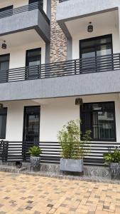 a white building with black windows and potted plants at Rugando apartment one bedroom (Whatsapp only : +250788784988) in Kigali