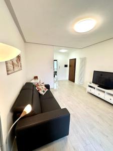 a living room with a black couch and a flat screen tv at Marta House in SantʼAmbrogio di Valpolicella