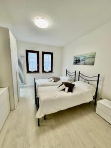 two beds in a large room with two windows at Marta House in SantʼAmbrogio di Valpolicella