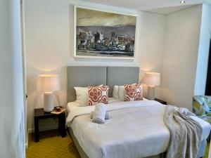 a bedroom with a large white bed with two lamps at Cartwrights in Cape Town +54 photos