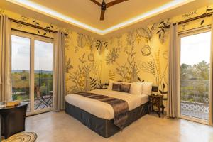 a bedroom with a bed with yellow walls and windows at Lotus Villa Goa in Mandrem
