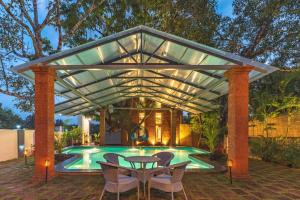 a pergola over a swimming pool with a table and chairs at Lotus Villa Goa in Mandrem