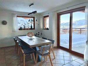 a dining room with a table and chairs and a window at Arc 1800, le Chalet Manaro avec sa vue panoramique in Bourg-Saint-Maurice