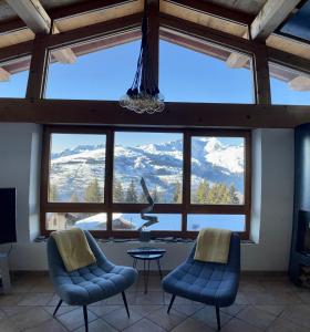 a room with two chairs and a large window with mountains at Arc 1800, le Chalet Manaro avec sa vue panoramique in Bourg-Saint-Maurice