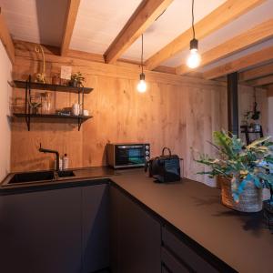 a kitchen with wooden walls and a counter with a sink at Hoogtij°d in Oostvoorne