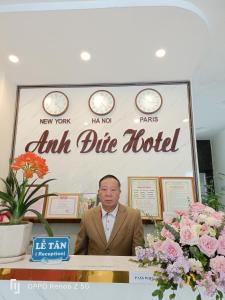 un hombre sentado en una mesa frente a una señal en Anh Duc Hotel en Tam Ðảo