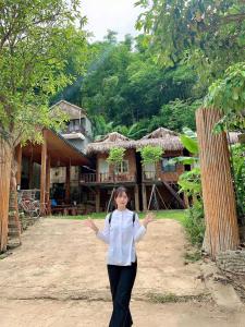 Green homestay Mai chau في ماي تشاو: امرأة تقف امام المنزل