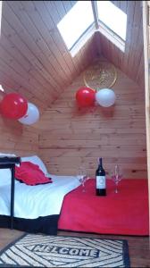 Hospedaje Guatavita cabaña tippie في جوتافيتا: غرفة بسرير مع كؤوس نبيذ وبالونات