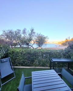 a table and chairs on a lawn with a view of the beach at Le NEUBURG Sur La plage Vue Mer Climatisation Piscine Parking in Sète