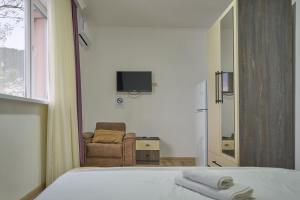 a bedroom with a bed and a chair and a television at Hotel Lile • სასტუმრო ლილე in Khulo
